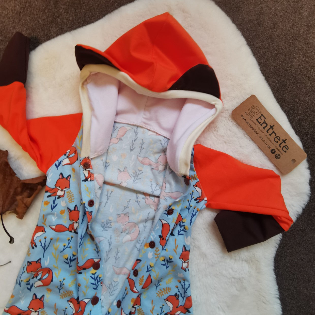 The adorable hooded fox romper, great for role play. Showing the hood with fun fox ears. Handmade using sky blue foxes, orange, brown and white cotton jersey's and cream cotton ribbing.