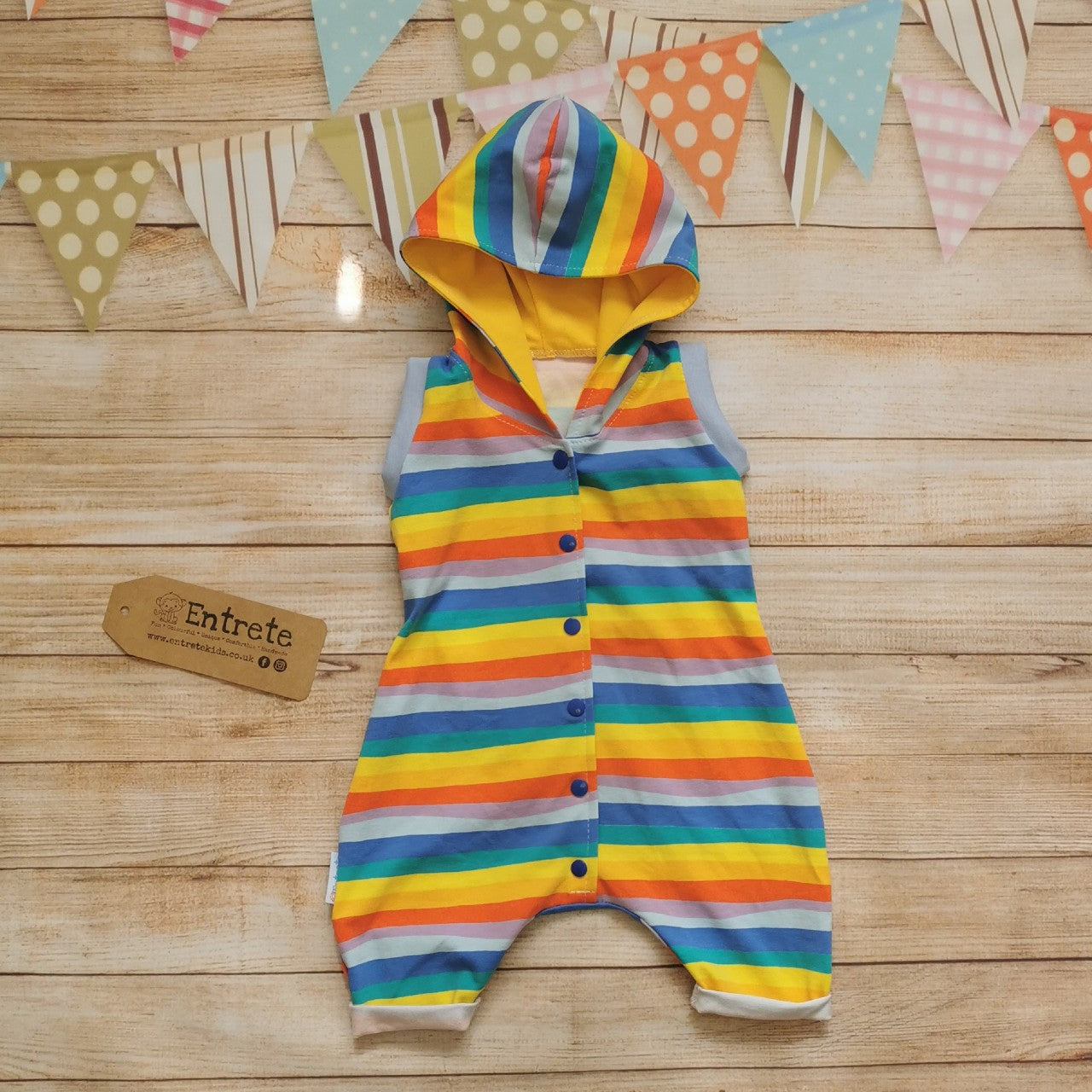 Front of Unisex Kids Hooded Bummie Romper, handmade in gorgeous red rainbow striped cotton jersey, with yellow organic cotton jersey hood lining and light blue cotton ribbing.