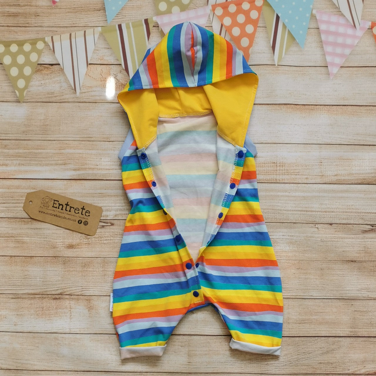 Unisex Kids Hooded Bummie Romper, handmade in gorgeous red rainbow striped cotton jersey, with yellow organic cotton jersey hood lining and light blue cotton ribbing. Showing easy front popper entry.