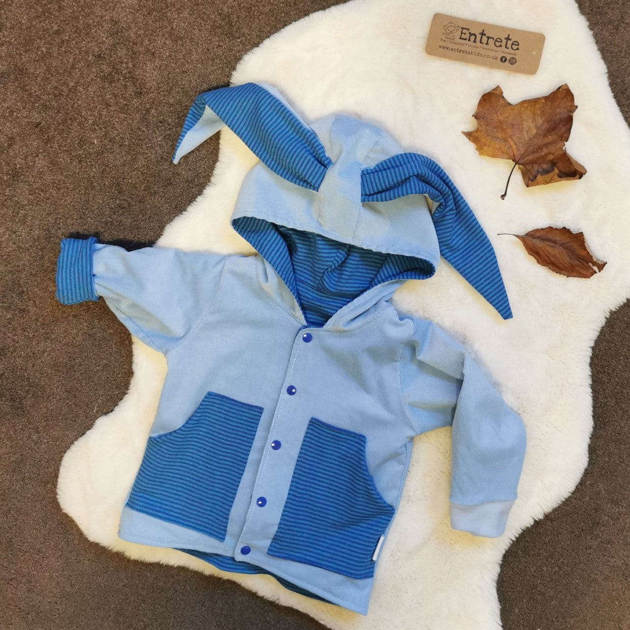 Blue corduroy bunny coat, with aqua and cobalt striped front pockets and bunny ears.