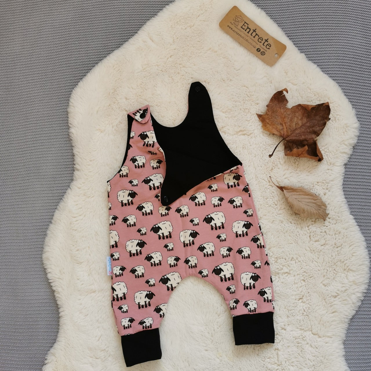 The adorably fun pink sheep romper. Handmade using pink sheep and black cotton jerseys'. Shown with one of the shoulder poppers open.